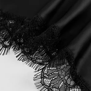 Detailed close-up showing the delicate eyelash lace trim on a black satin skirt hem.