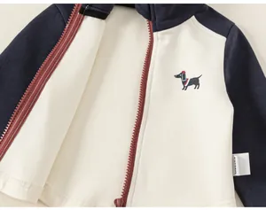 Gros plan d'une veste zippée pour enfant marine et crème avec broderie teckel.