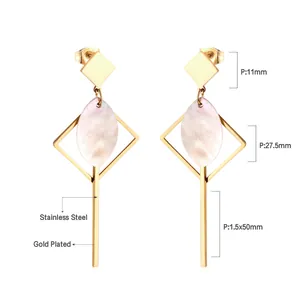 Détail rapproché de boucles d'oreilles géométriques en acier doré avec incrustation