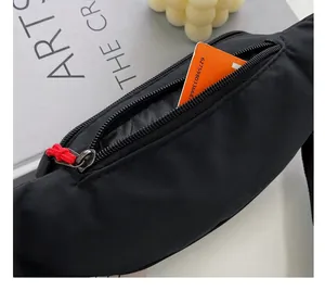 Detail view of black nylon fanny pack showing functional zipper pocket and red puller