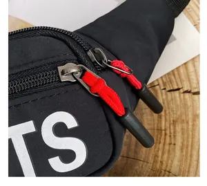 Close-up detail of black chest bag featuring white letter print and red rope zippers