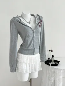 Close-up of a grey hooded zip-up sweatshirt featuring a red athletic letter print detail