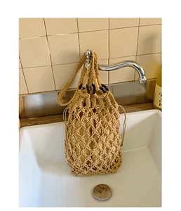 Hand-woven beige macrame hollow handbag with a vintage design shown hanging from a faucet