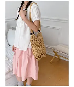 Detailed shot of a beige macramé woven net handbag with inner pouch on a model