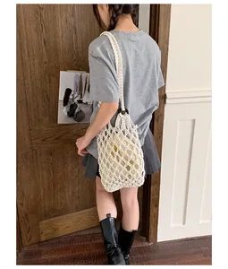 Vintage white hand-knotted net bag with lining pouch, styled on a model's shoulder