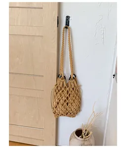 Detailed view of a handmade woven hollow shoulder bag hanging on a vintage wooden door