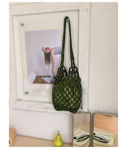 Close-up detail of green hand-woven hollow mesh bag featuring a drawstring inner pouch