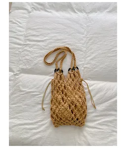 Hand-woven beige macramé mesh shoulder bag with drawstring inner pouch on white fabric