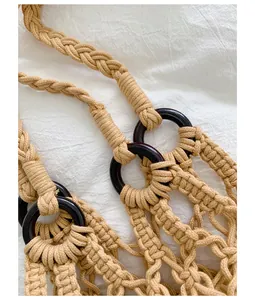 Detail view of the intricate hand-woven macrame texture and dark wooden rings on the bag
