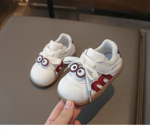 Detailansicht der weißen Kinderschuhe mit rotem M-Logo und niedlichen Comic-Augen