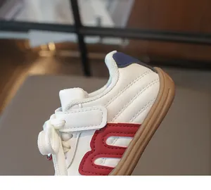 Nahaufnahme weißer Kinder-Lederturnschuh mit rotem Seitenmuster und Gummisohle