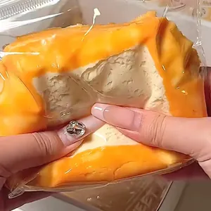 Close-up view of a soft silicone toasted mochi squishy toy being squeezed by hand