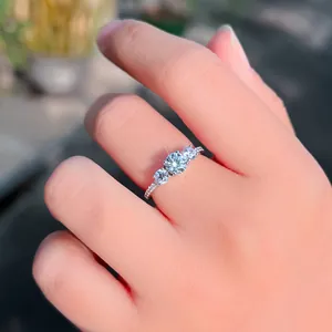 Detailaufnahme eines funkelnden S925-Silberrings mit drei Steinen an einem Finger