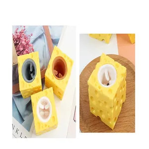 Detailaufnahme des gelben Käse-Maus-Quetschspielzeugs auf einem Holzteller mit Requisiten
