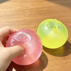 Giocattoli sensoriali a forma di mela traslucida in rosa e verde su tavolo di legno