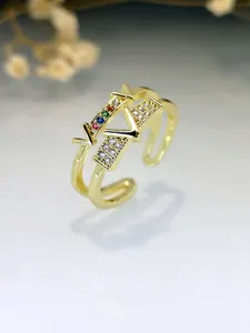 Close-up of gold V-letter ring with multi-color and clear zircon inlays.