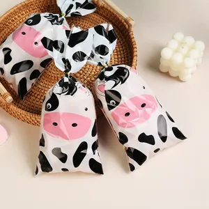 Cute cartoon cow print OPP candy bags for party gift packaging with gold twist ties.