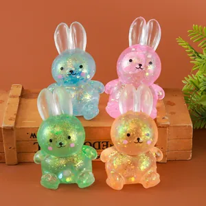 Vue détaillée de quatre jouets lapin squishy pailletés sur une caisse en bois rustique