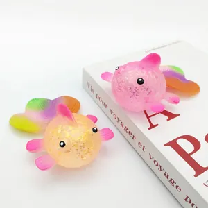 Macro view of two colorful glittery goldfish squeeze toys resting on a white art book.