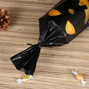 Halloween black plastic treat bag with pumpkin face design tied on wooden surface