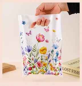 Mano que sostiene una bolsa de regalo de plástico blanca con flores y mariposas