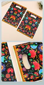 Close-up detail of ethnic floral pattern on black plastic gift bag with handle cut-out