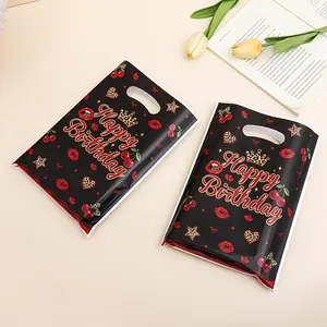 Two black Happy Birthday plastic gift bags with cherry and lip patterns on beige background