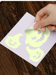 Détail d'une main décollant un autocollant d'Halloween fluorescent pour décoration