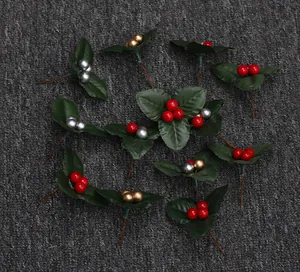 Multiple artificial Christmas holly sprigs with red gold and silver berries on grey background