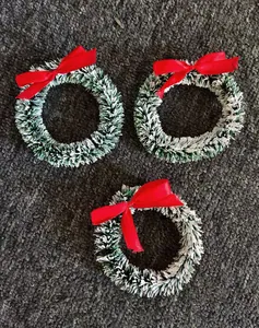 Set van drie mini-kerstkransen met besneeuwde toppen en rode strikken op grijs