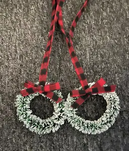 Detail of mini frosted Christmas wreaths featuring red and black buffalo plaid ribbons