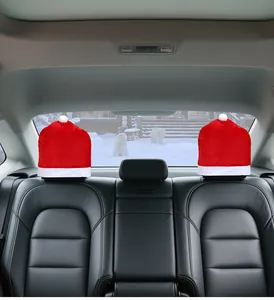 Red Santa hat headrest covers on black leather car seats against a snowy outdoor background