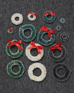 Macro view of mini sisal Christmas wreaths in green, white, and black with red bows.