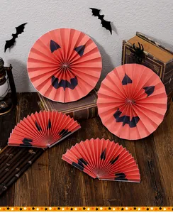 Close-up of Halloween orange pumpkin paper fans with demon face designs for party decor