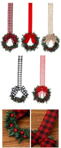 Detail van een kerstkrans voor de kast met rood geblokt lint en decoratieve rode bessen