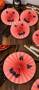 Close-up detail of orange Halloween Jack-o'-lantern pleated paper fan decorations