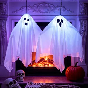 Pair of glowing white LED Halloween ghost decorations hanging by a cozy fireplace background