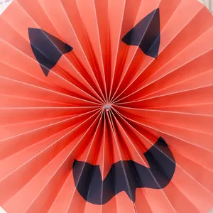 Vibrant Halloween orange pleated paper fan flower with spooky pumpkin face design