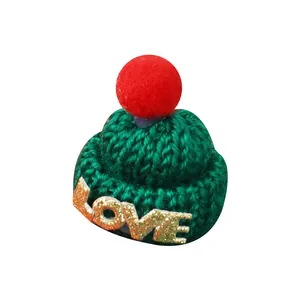 Mini green knitted Christmas hat with red pom-pom and golden LOVE glitter accessory