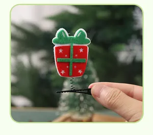 Detailed close-up of a festive Christmas gift box hair clip on a spring and alligator clip.