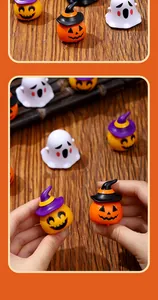 Dettaglio macro di mini auto a molla zucca e fantasma di Halloween tenute in mano per scala