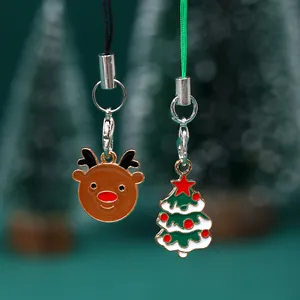 Lindos llaveros navideños de aleación con dijes de reno y árbol sobre un fondo verde oscuro