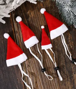 Detail view of four mini pet Christmas hats with adjustable elastic bands on wood