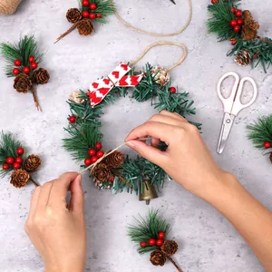 Handmade DIY Christmas wreath featuring mini pine needles, pine cones, and festive red berries
