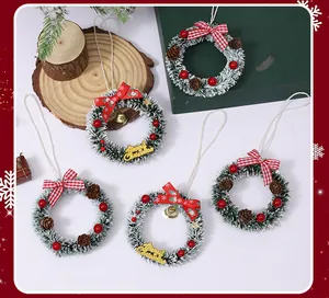 Detalle de mini coronas de Navidad con piñas, lazos rojos y efecto de nieve.