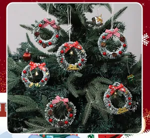 Primer plano de mini coronas navideñas nevadas con lazos rojos y piñas en el árbol