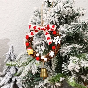 Mini Christmas rattan wreath with red heart bow and golden bell on a snowy tree