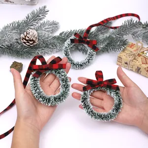 Mini Christmas wreaths with red and black buffalo plaid bows held by hand