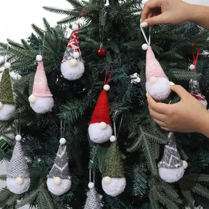 Various knitted Christmas gnome hanging ornaments with pompom beards on a green tree