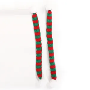 Detailweergave van mini gebreide kerstsjaals met rode en groene strepen voor poppen